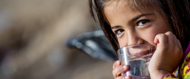 Une petite fille d'Irak boit un verre d'eau.
